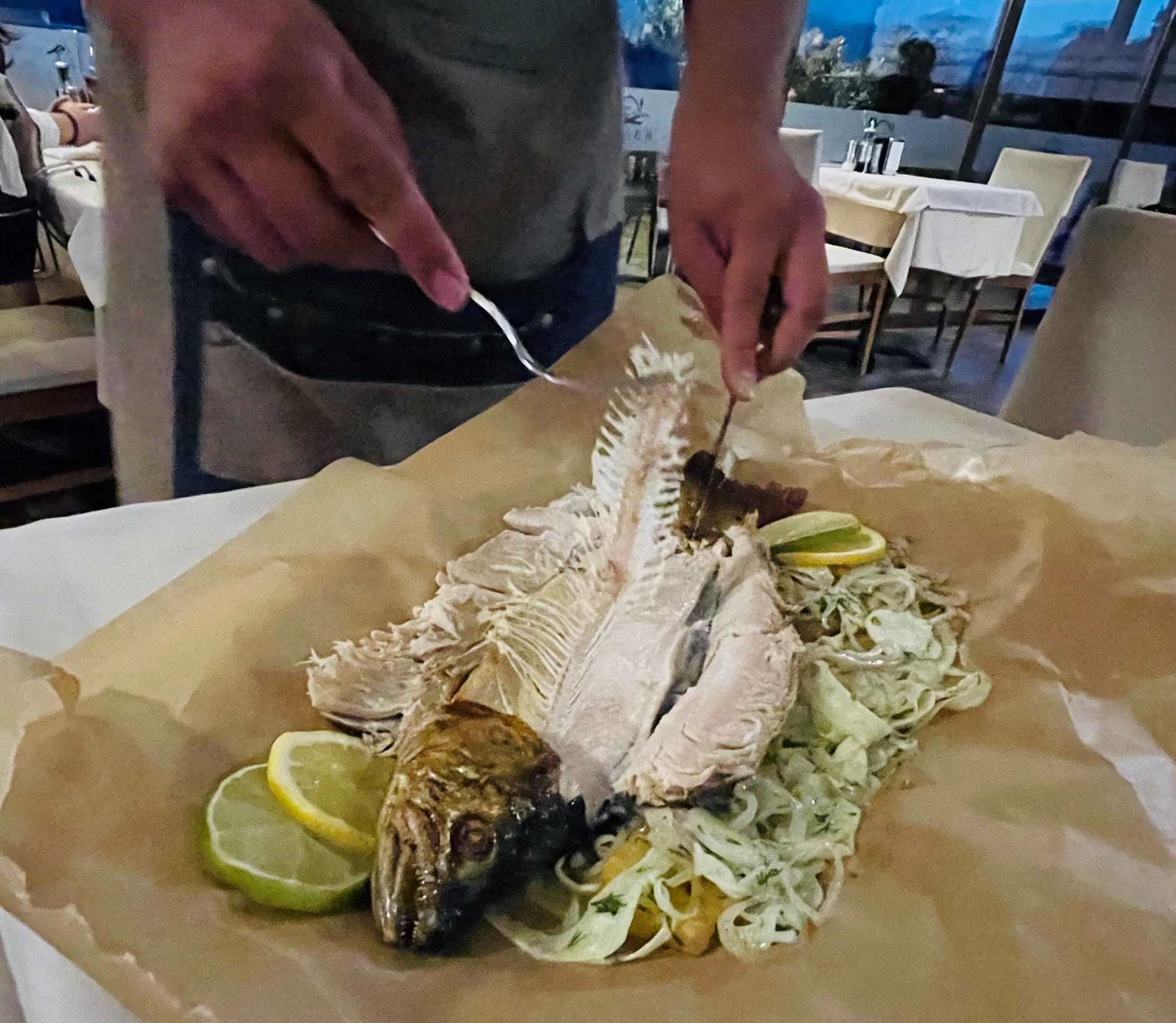 Waiter removing bones from fish on a plate of pasta in North Macedonia